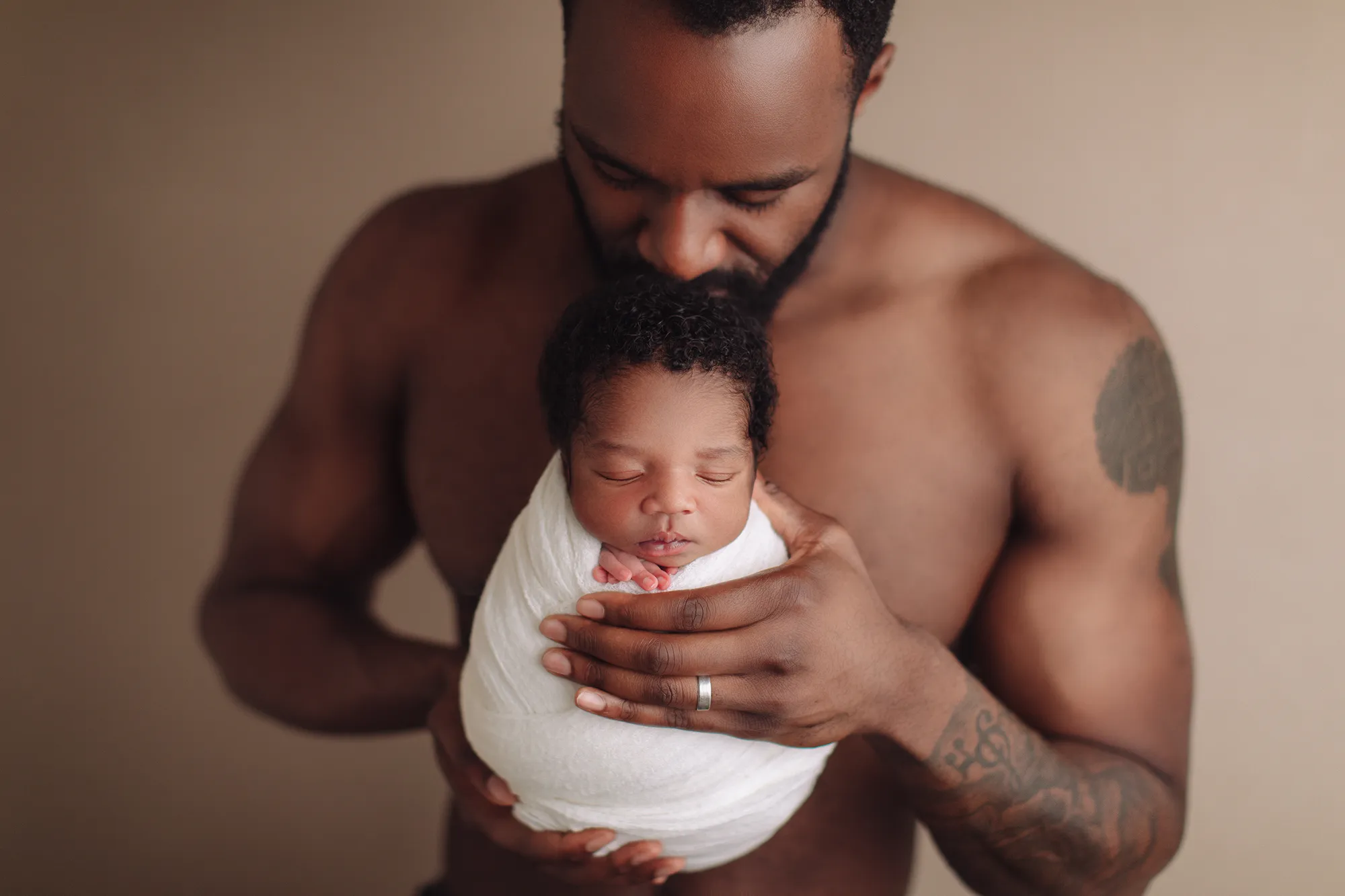 Father holding his swaddled newborn daughter against his chest